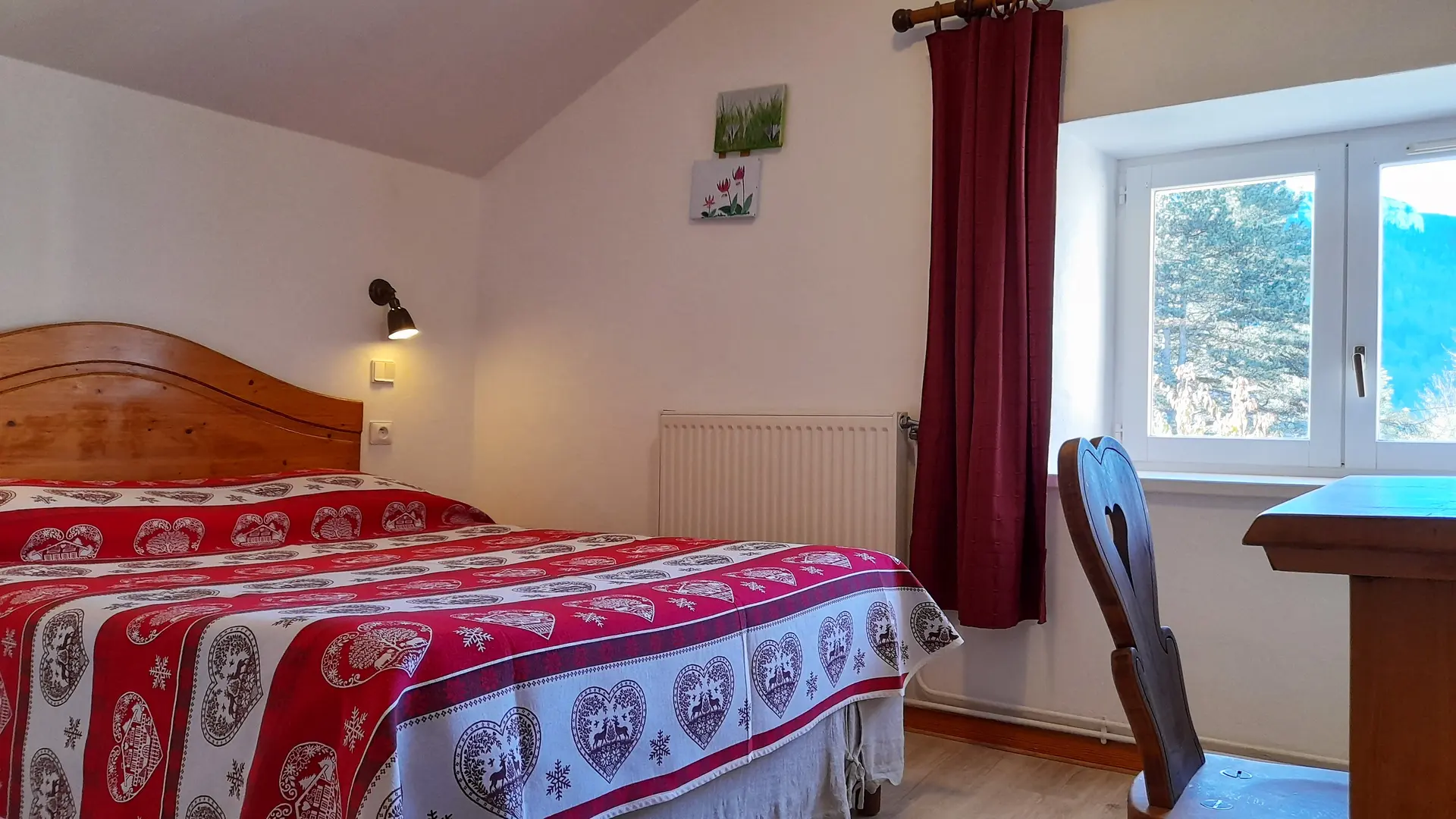 Chambre double lumineuse équipée d’un bureau et d’une chaise en bois avec une fenêtre laissant entrer la lumière naturelle