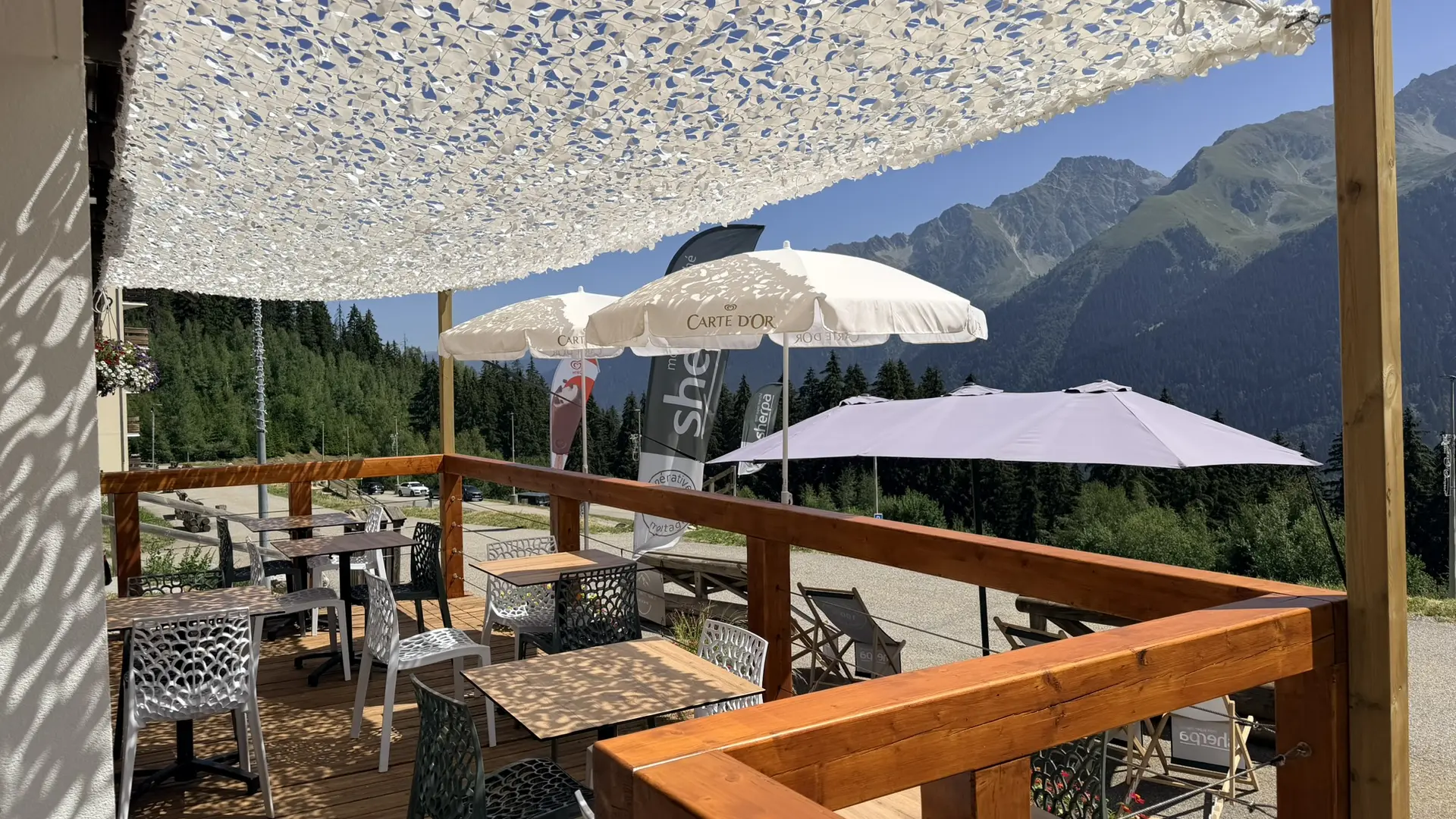 Terrasse du Sherpa au Pleynet avec des tables et parasol vue sur le massif de Belledonne