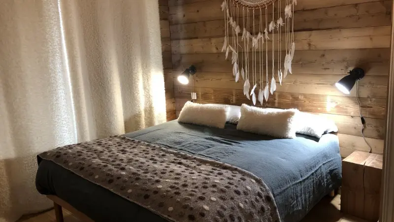 Chambre lumineuse avec lit double, ameublement en bois, rideaux et fenêtre