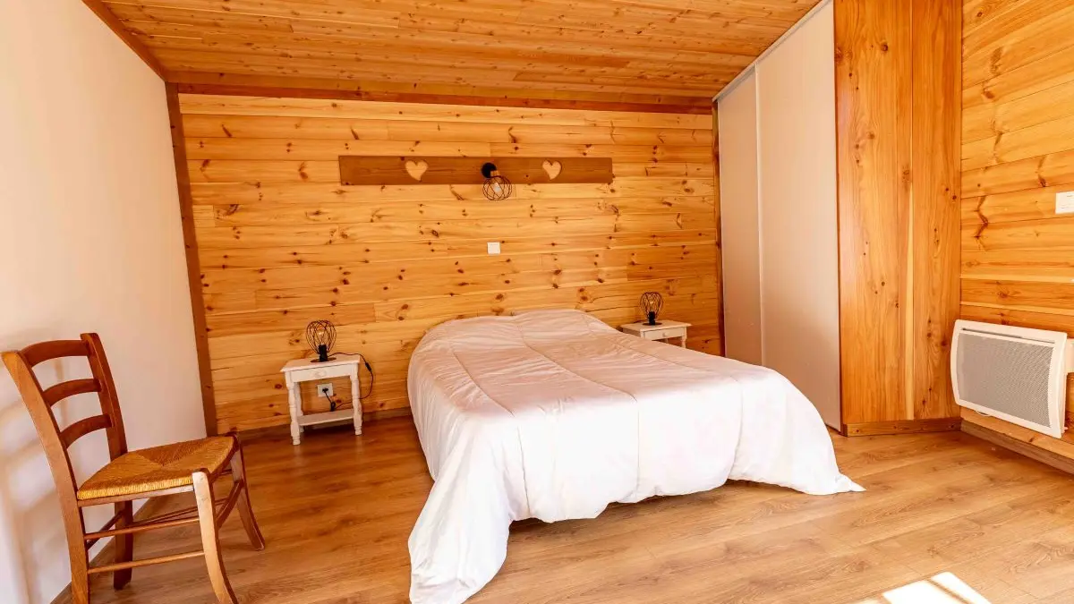 Chambre à coucher lumineuse avec lit double, ameublement bois, parquet au sol, fenêtre