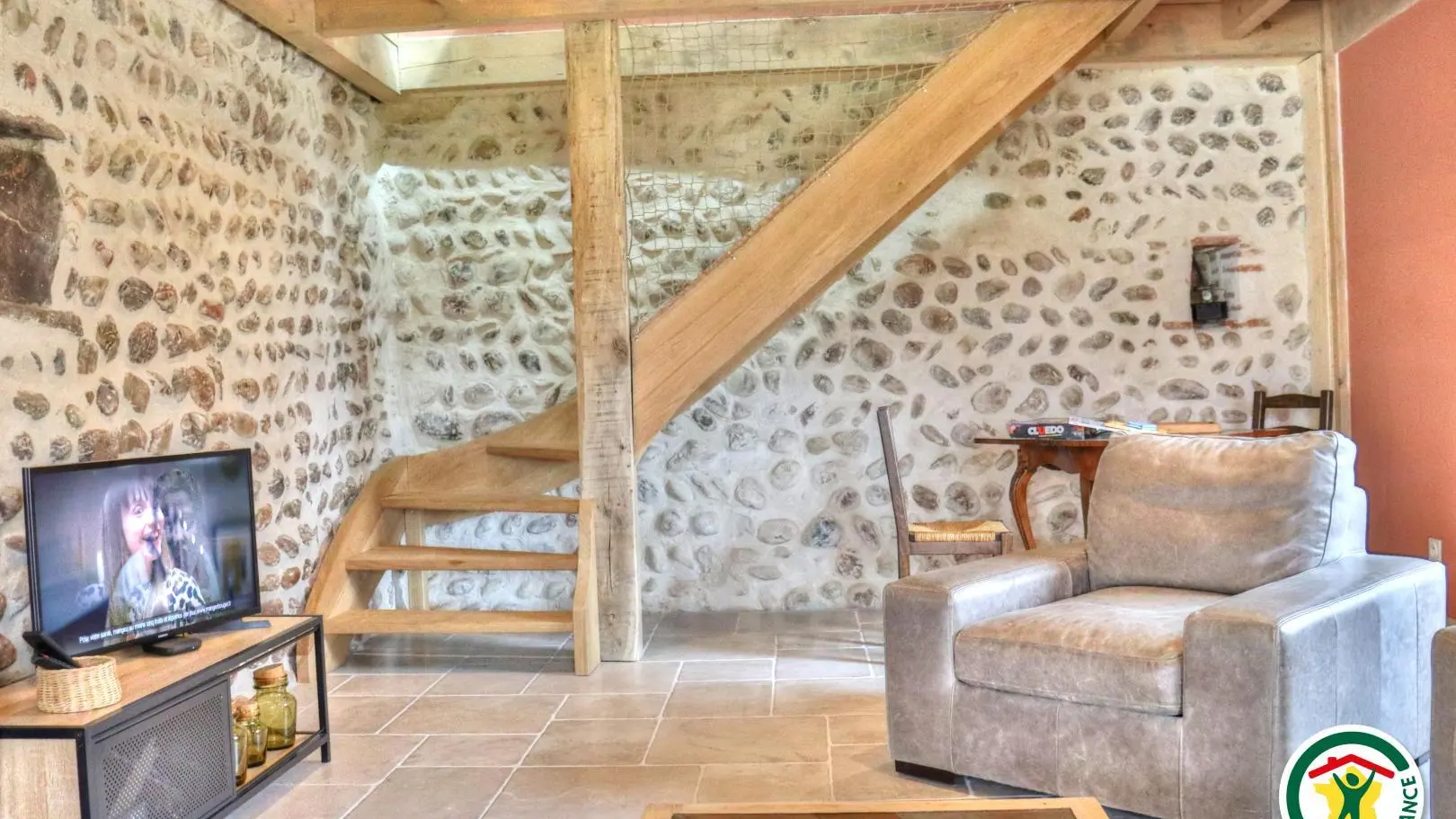 Salon avec coin TV et coin jeux. Escalier qui monte aux chambres à l'étage