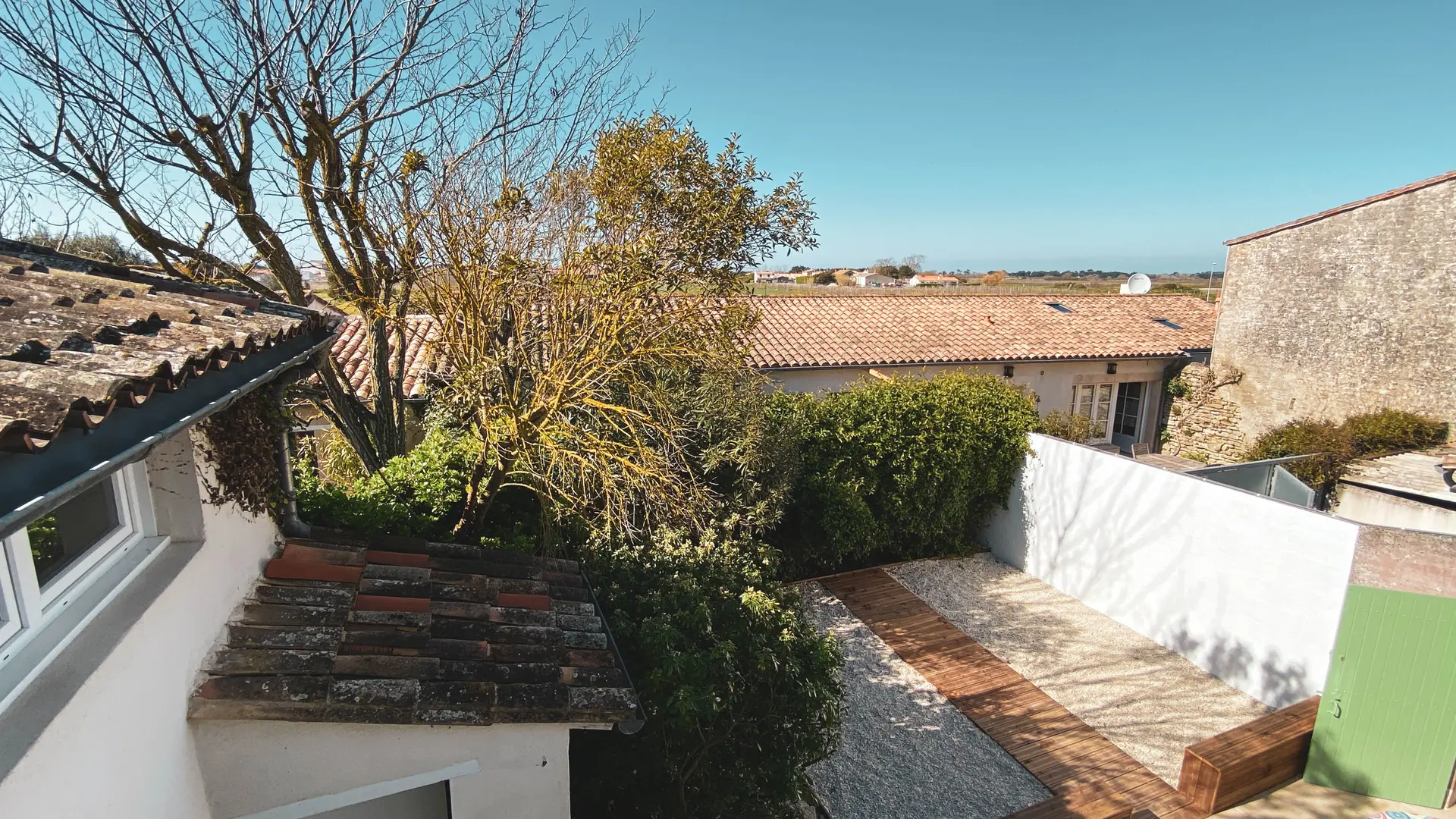 Vue de la terrasse extérieure des Fillattes par la fenêtre de la chambre n°2: terrasse rénovée en 2020