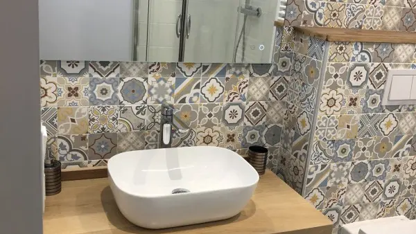 Salle de bains lumineuse, carrelage, évier, miroir et toilettes