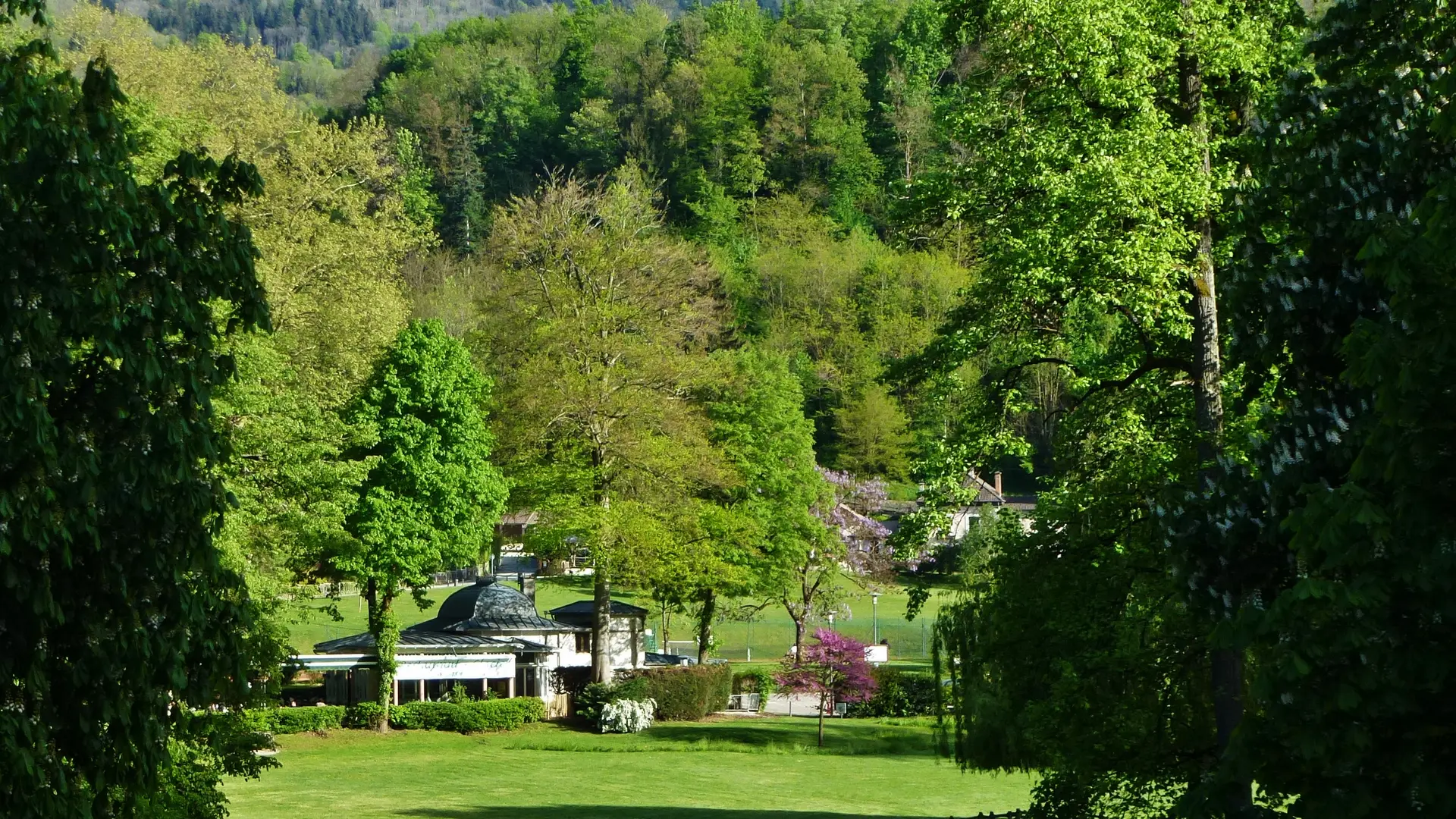 Vue du séjour sur le parc et l'établissement thermal d'Uriage au printemps.