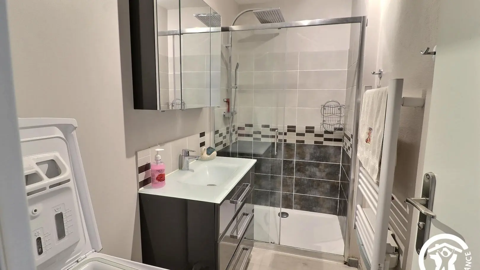 Salle d'eau avec douche, sèche-serviettes et lave-linge