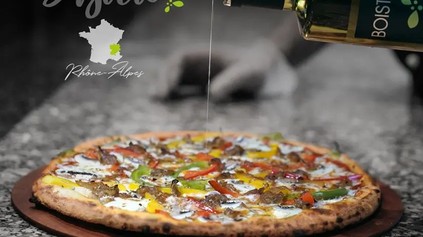 De l'huile pimentée est ajoutée à la garniture d'une belle pizza végétarienne