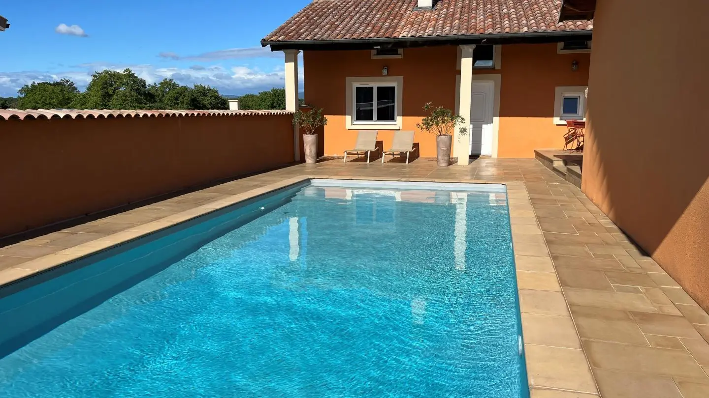 Le gîte propose une terrasse couverte, comprenant deux bains de soleil et un salon de jardin, avec vue sur la piscine.