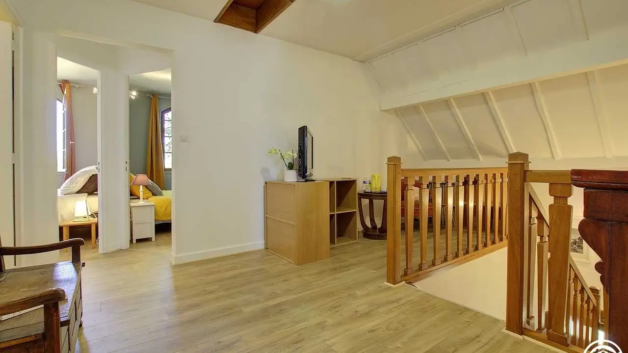 En haut des escaliers, un espace détente dédié aux hôtes (TV et plateau de courtoisie) et les deux chambres.