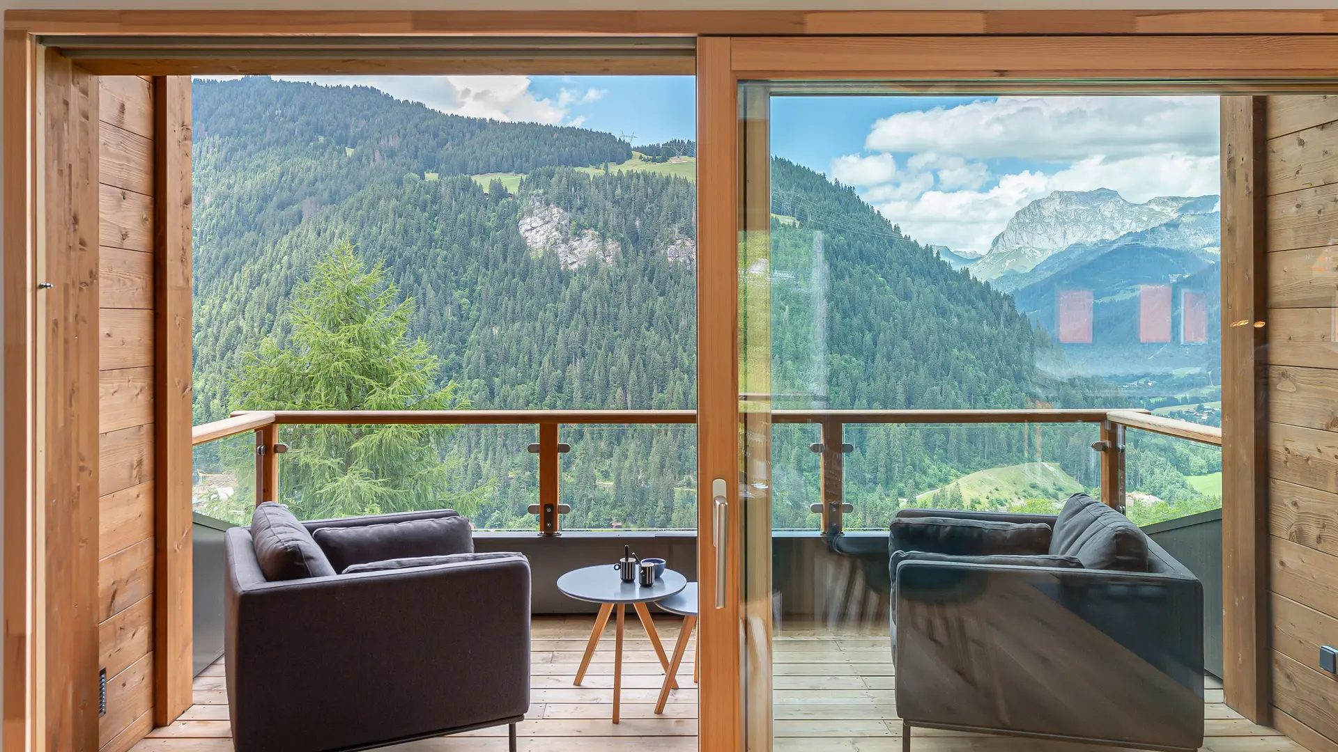 Balcon avec fauteuils, table basse, vue panoramique sur les montagnes et le village