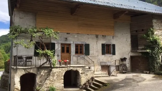 Vue sur maison depuis la route, avec place parking sur la droite.