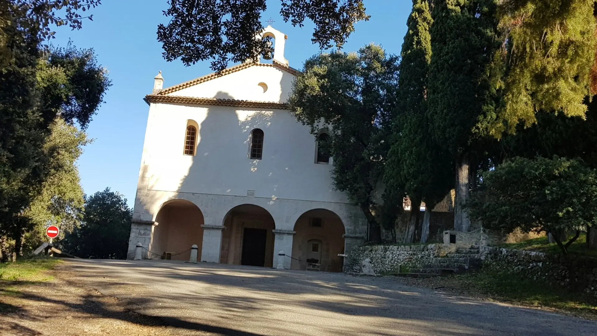 Chapelle à la façade blanche composée de 3 ouvertures voutées et 3 fenêtres avec vitraux et un petit clocher au sommet