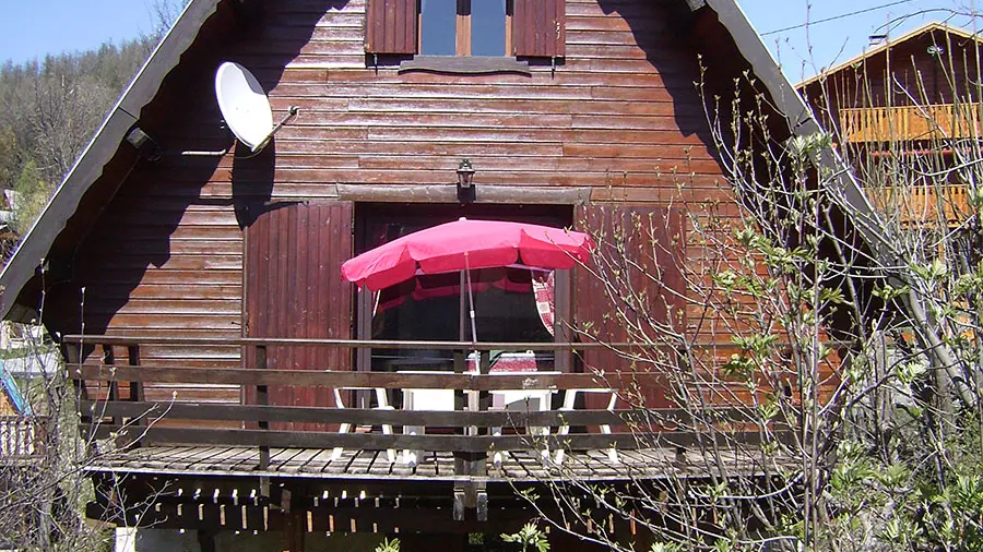 chalet en bois ensoleillé avec terrasse, fenêtres