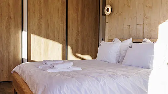 Large and bright bedroom, wood furniture, double bed, parquet flooring