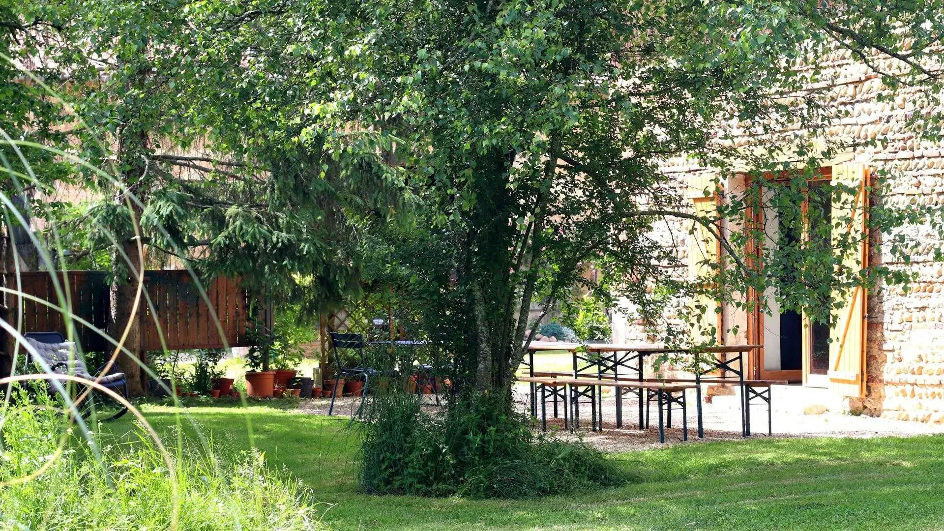 La terrasse ombragée sous les arbres devant l'entrée