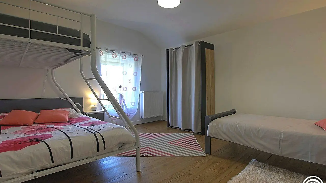 Chambre composée d'un lit superposé avec un lit double en bas, un lit simple en hauteur et un second lit simple indépendant.
