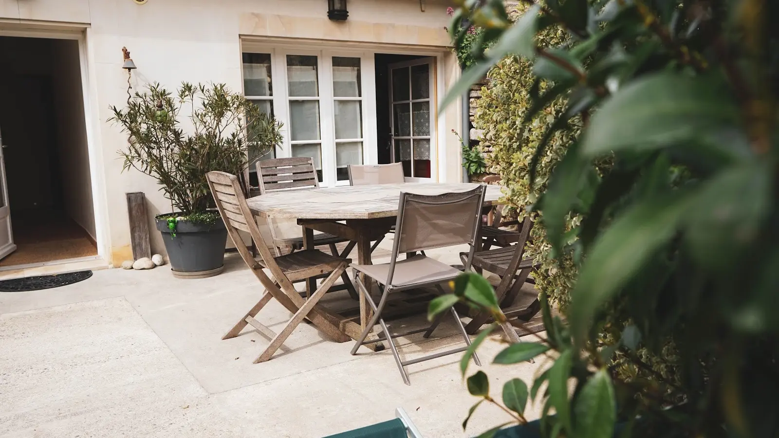 Autre vue de l'entrée principale avec la terrasse et son salon de jardin, accès direct à la cuisine par la porte fenêtre