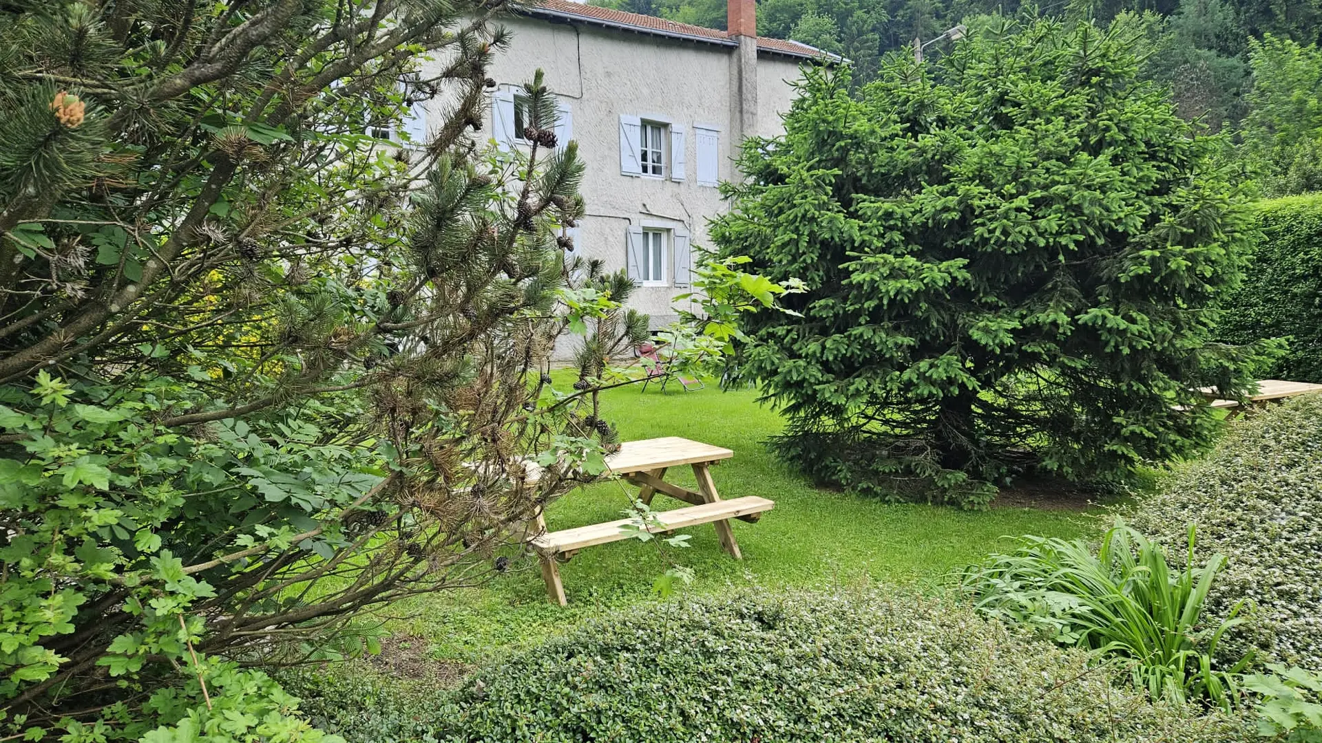 Dans le jardin, on trouve deux tables de pique-nique et des chaises longues.