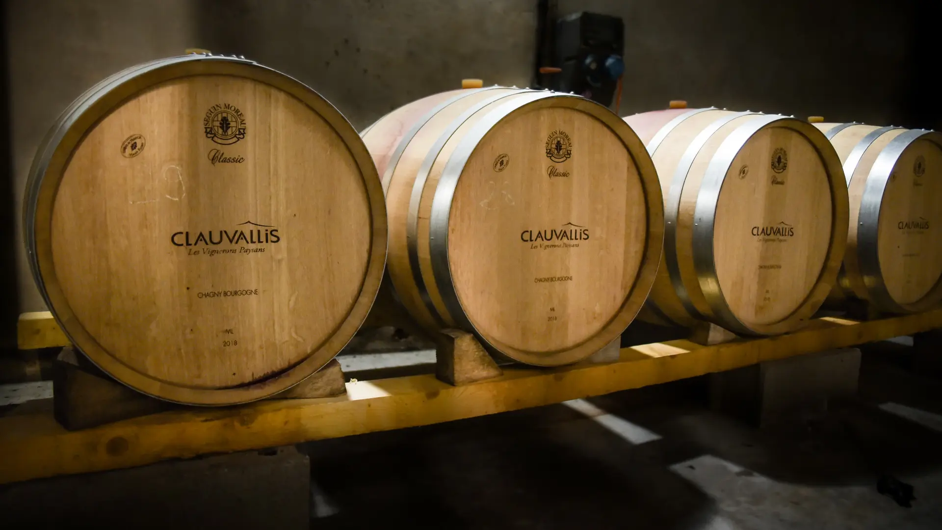 Rangée de fûts de chêne Clauvallis, symbole du vieillissement et du savoir-faire viticole.