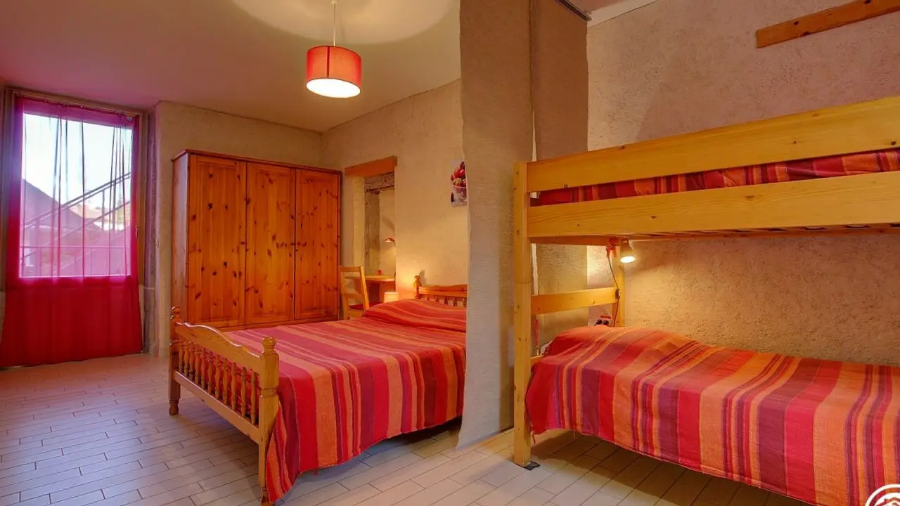 Chambre cerise avec 1 lit double et  lit simples superposés. Il y a une salle d'eau propre à cette chambre.