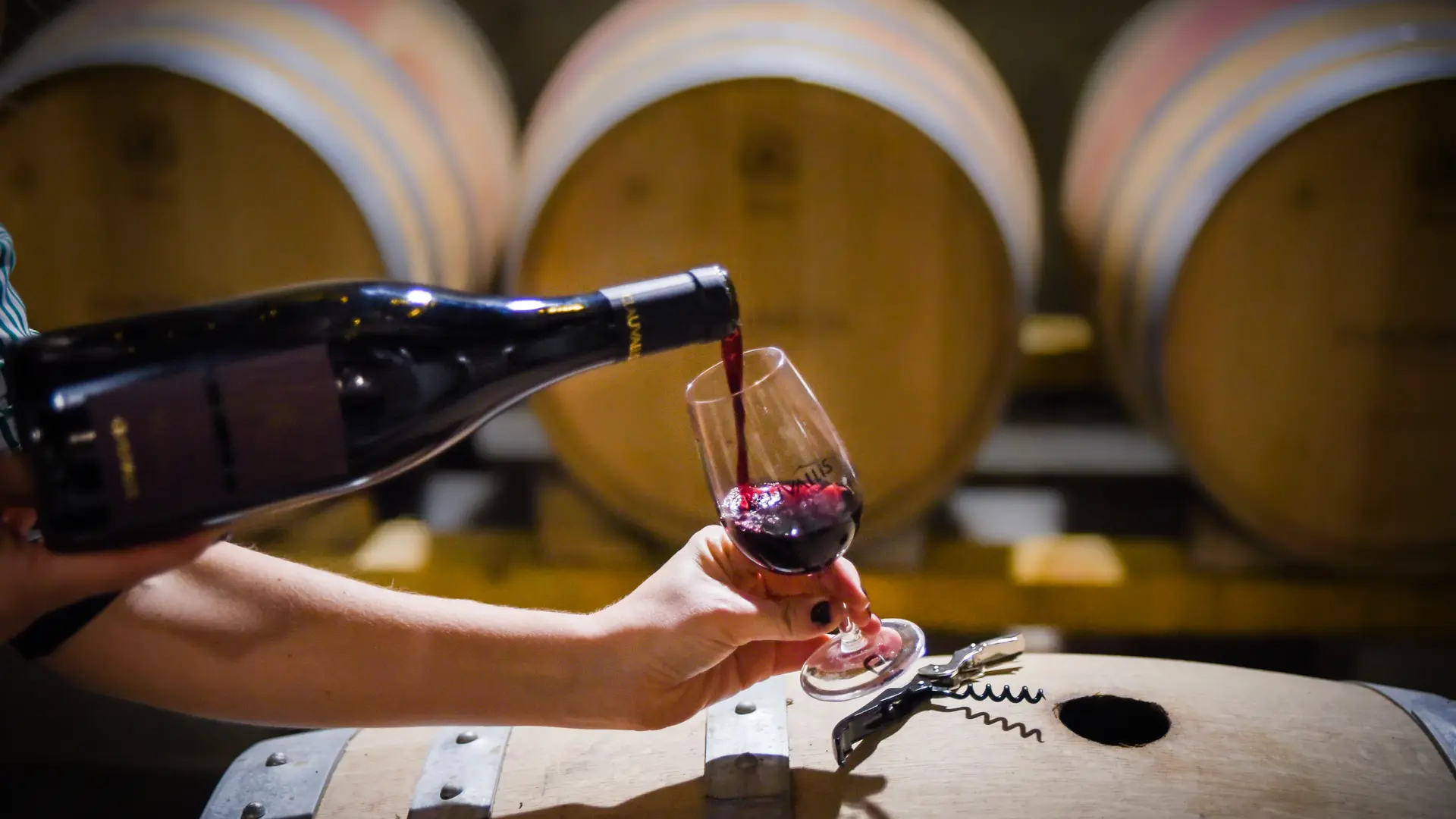 erre de vin rouge Clauvallis servi à la bouteille devant les barriques.