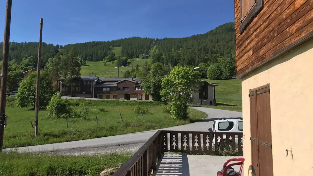 Terrasse en bois du chalet, vue dégagée sur la montagne en été