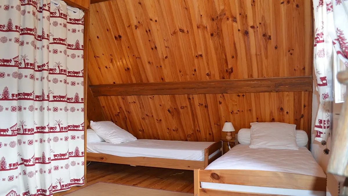 chambre à coucher d'enfant lumineuse sous combles avec deux lits simples et fenêtre