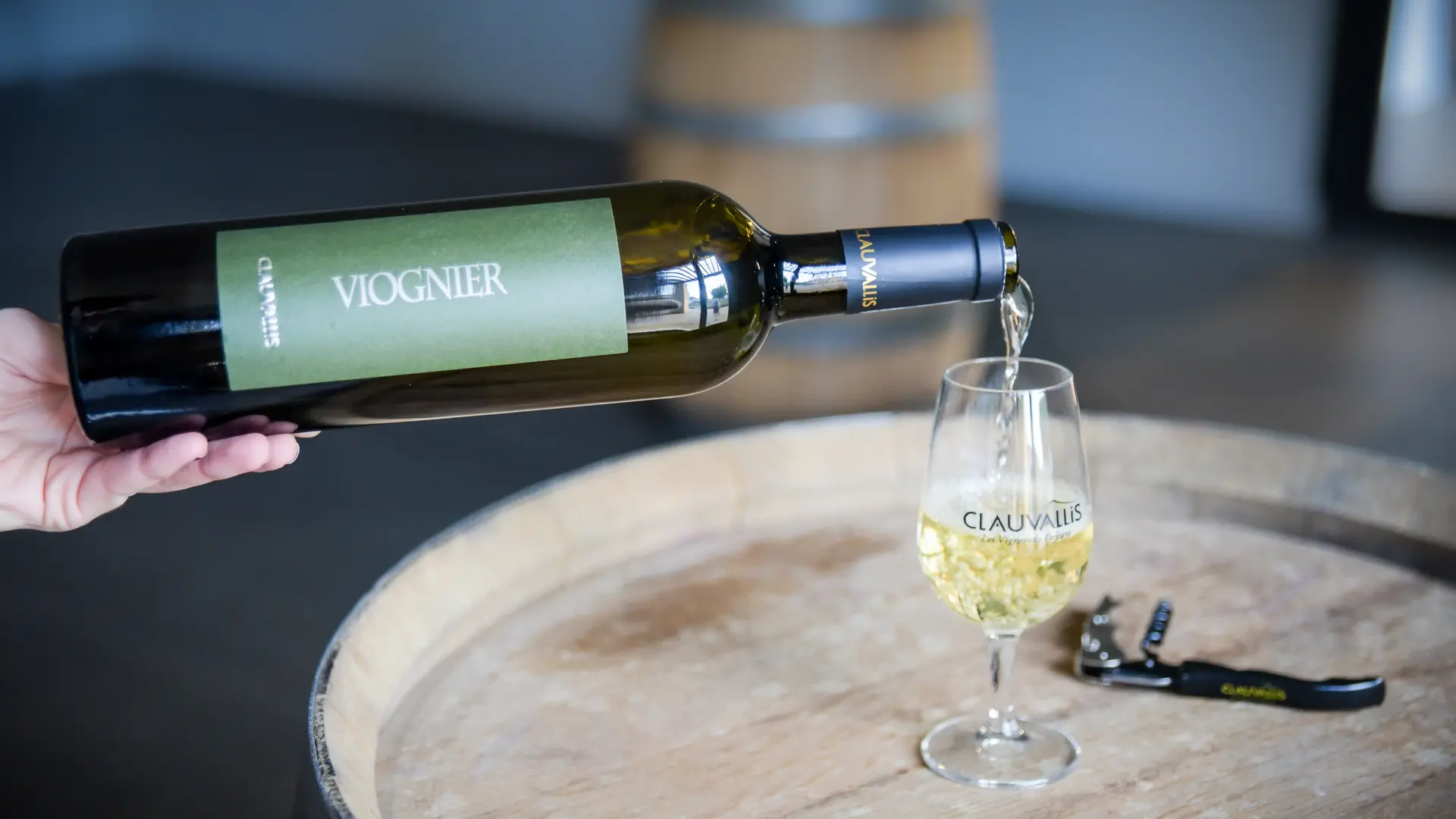 Bouteille de Viognier Clauvallis versant un vin blanc élégant dans un verre de dégustation.