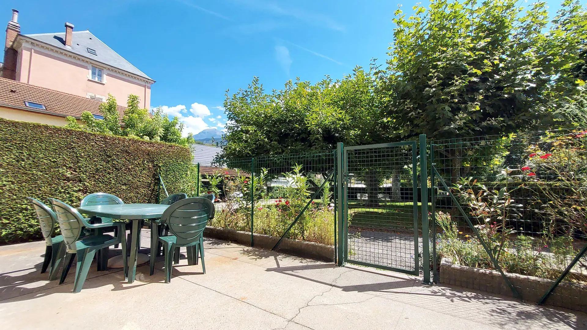 Une terrasse extérieure avec une table et des chaises donnant sur un jardin.