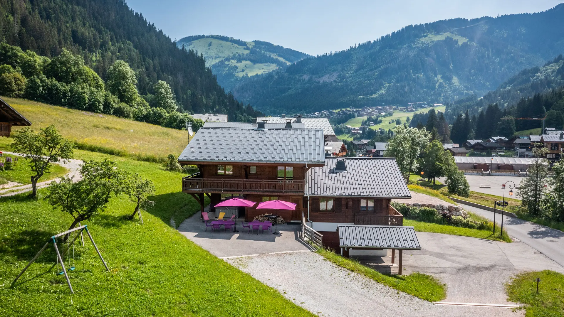 Extérieur du chalet en été avec terrasse et vue sur le village