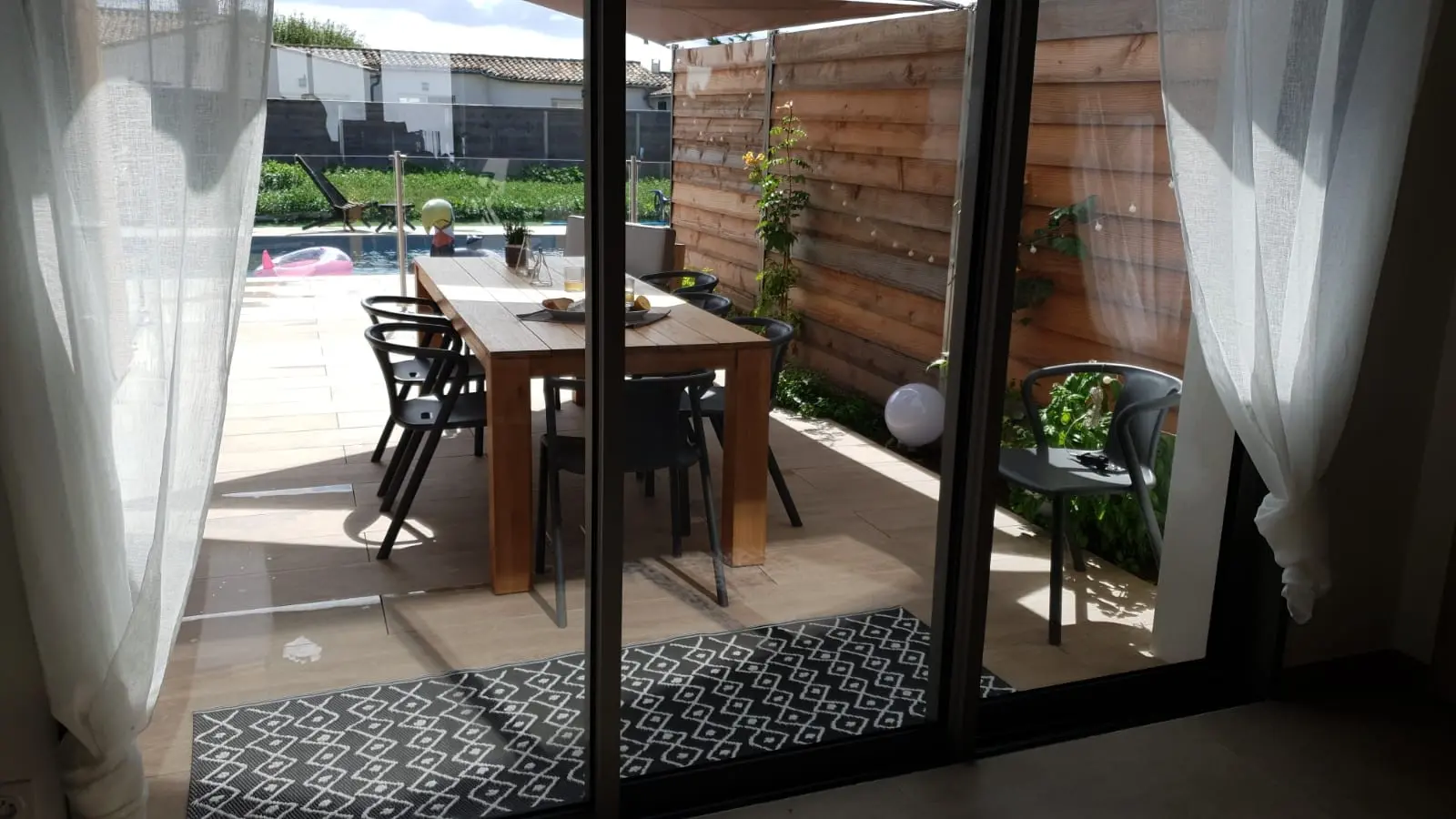 Vue du salon sur la terrasse, la piscine et le jardin