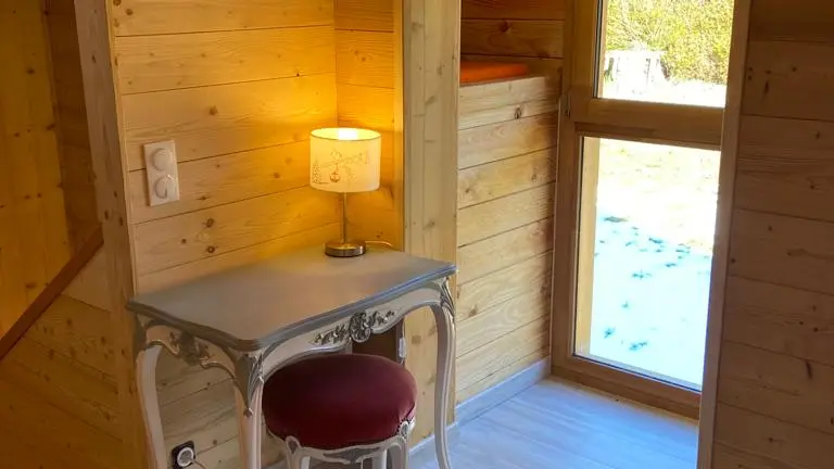 Pièce tout en bois, style chalet avec un petit bureau et une lumière tamisée.