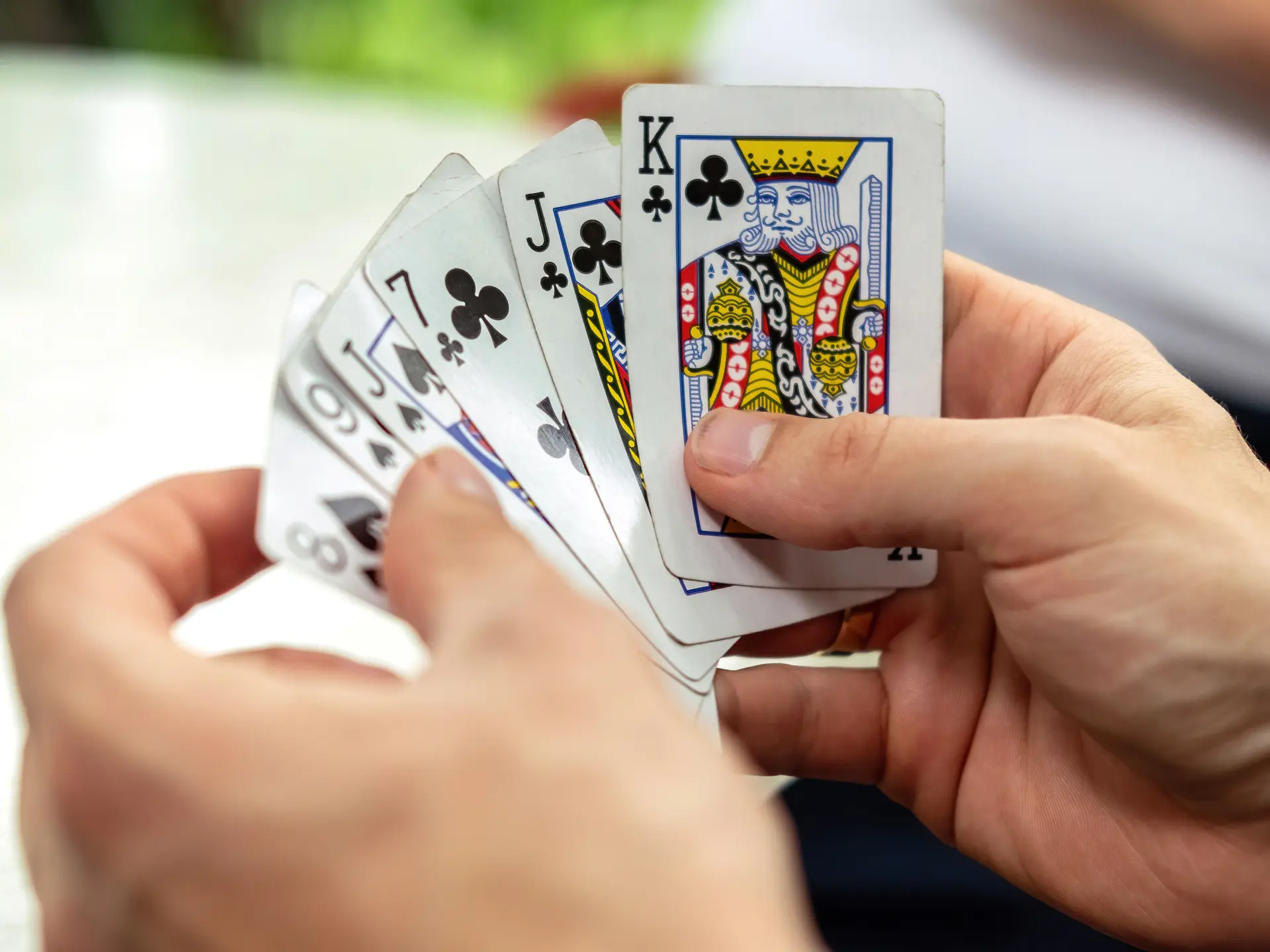 A man playing cards with other people holding a deck