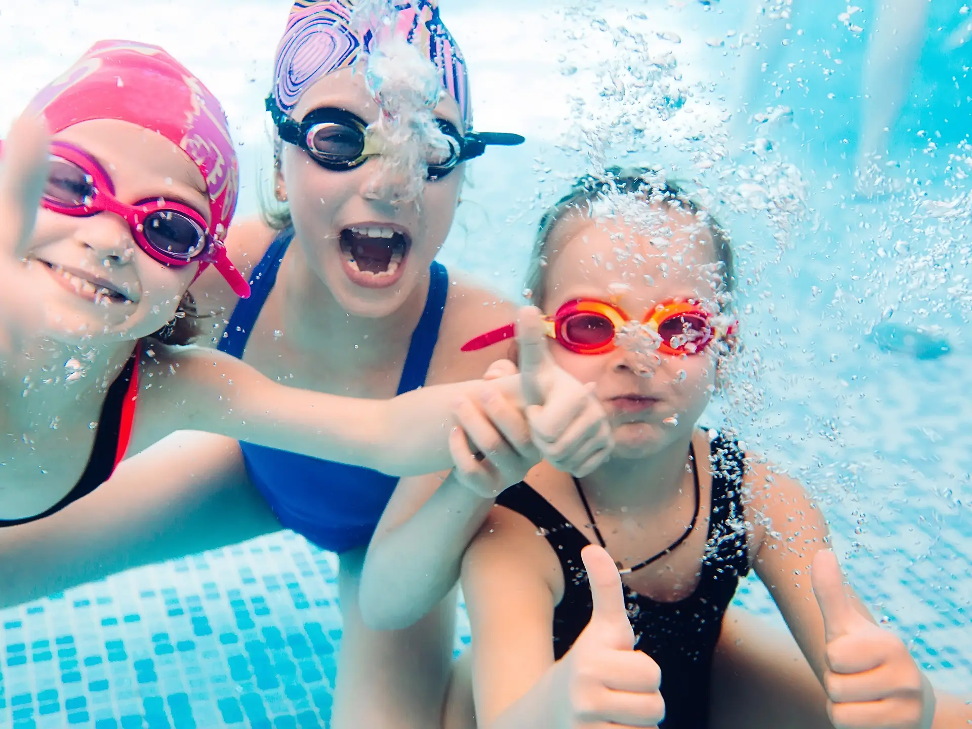 Underwater photo of young friends in swimming pool.