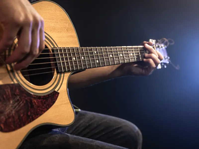 Close-up shot of guitarist playing acoustic guitar, copy space.