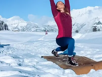 Personne pratiquant le yoga sur un tapis dans la neige