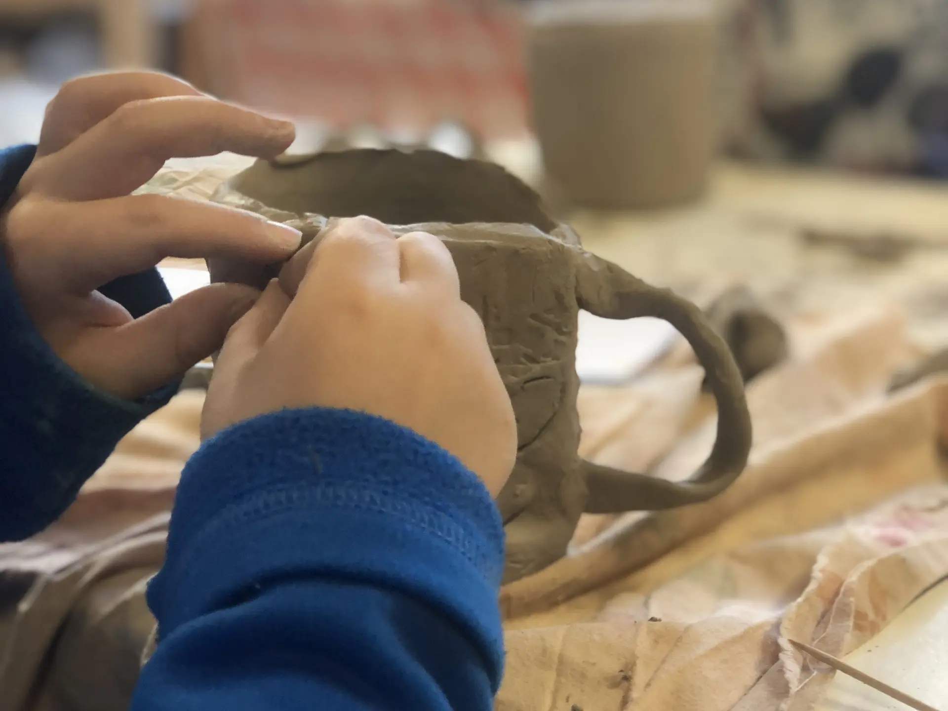Fabrication d'une tasse en terre réalisée par les mains d'un enfant.
