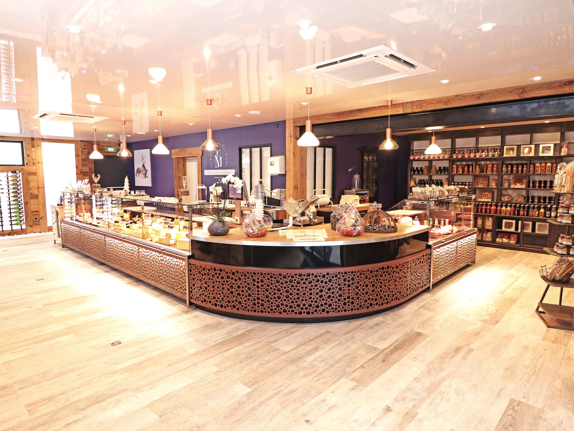 Entrée du magasin des Délices de Margot, avec un comptoir arrondi au premier plan et des étagères avec des produits dans le fond.