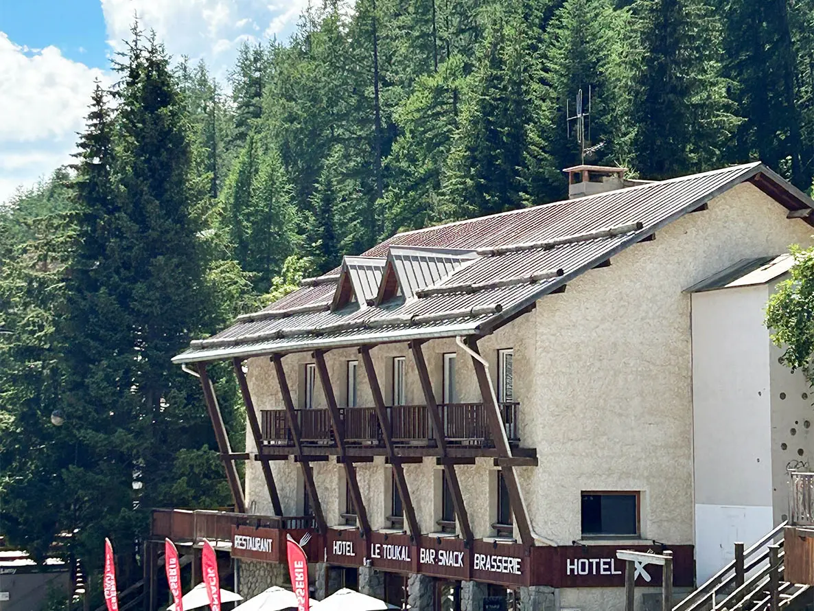 Vue de la brasserie sur 3 étages, bâtiment en pierre et bois avec terrasse en rdc et balcons
