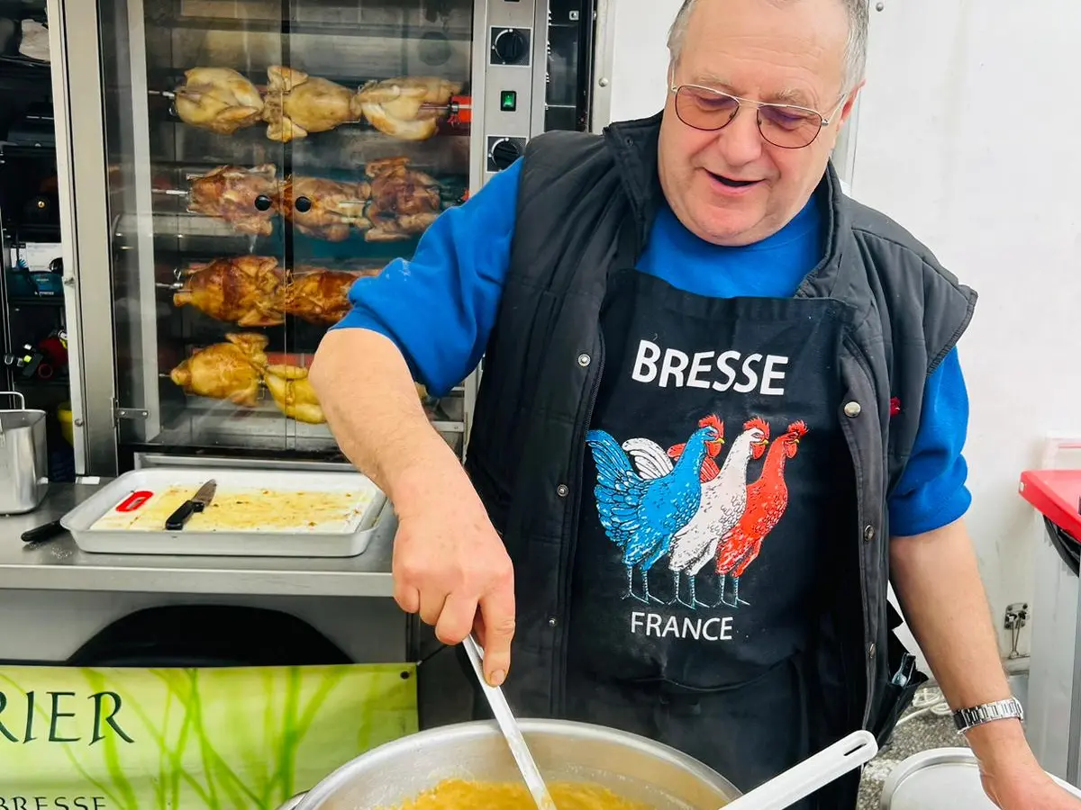 Joël Billet préparant le poulet de Bresse à la crème au marché Cerdon Cuivrerie en mars