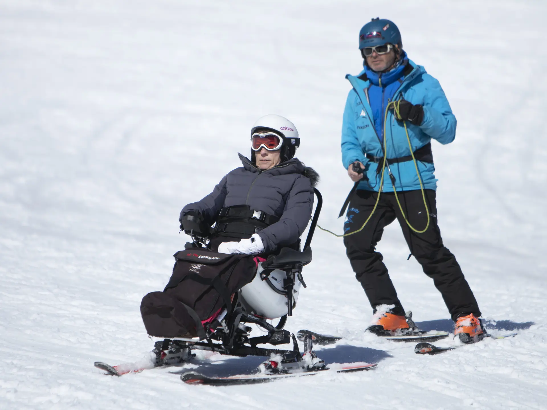 Une personne en Tétraski avec un moniteur sur une piste de ski