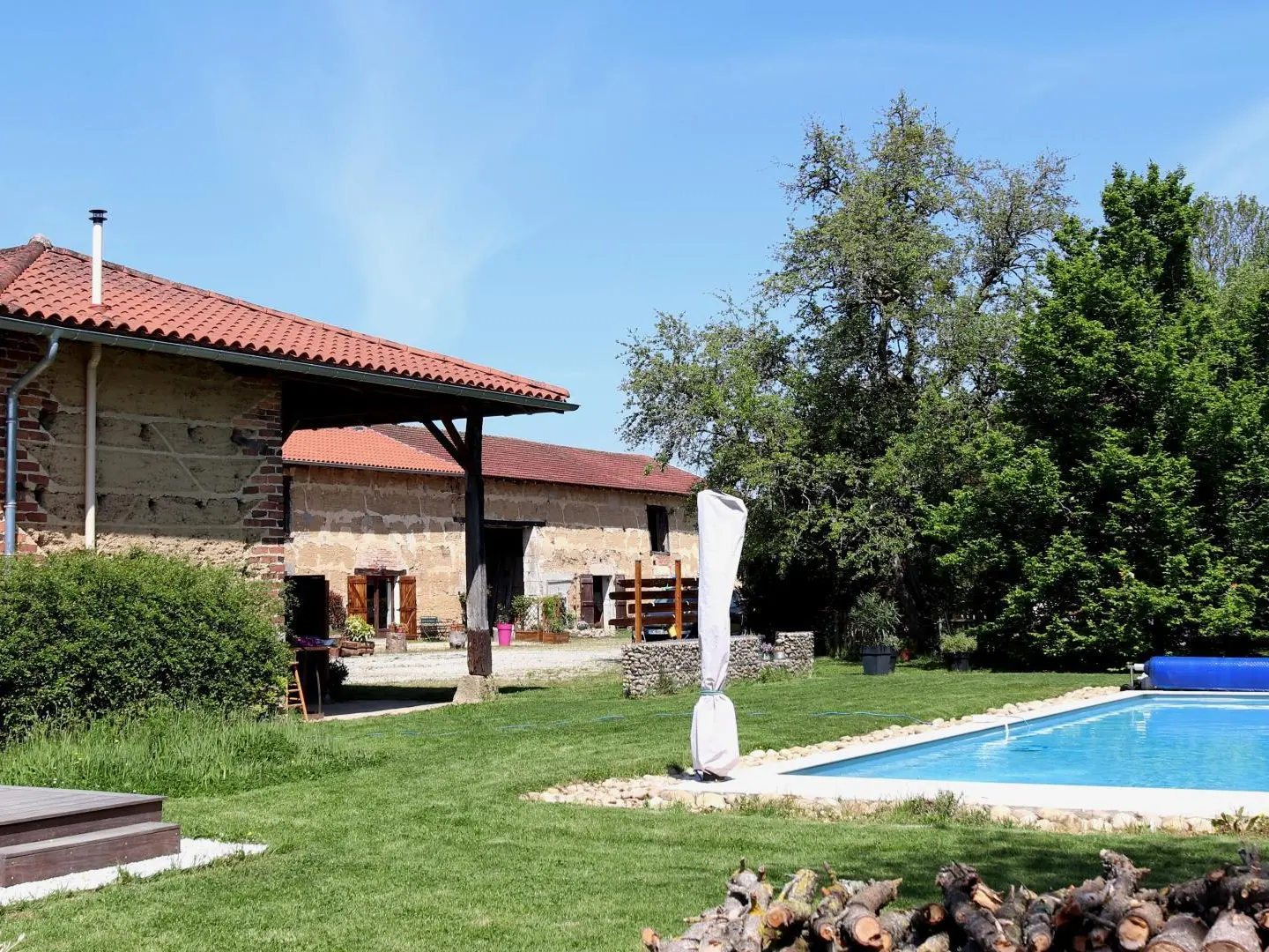 La piscine et l'espace jeux sous le hangar, avec vue sur le gîte L'Etable au fond