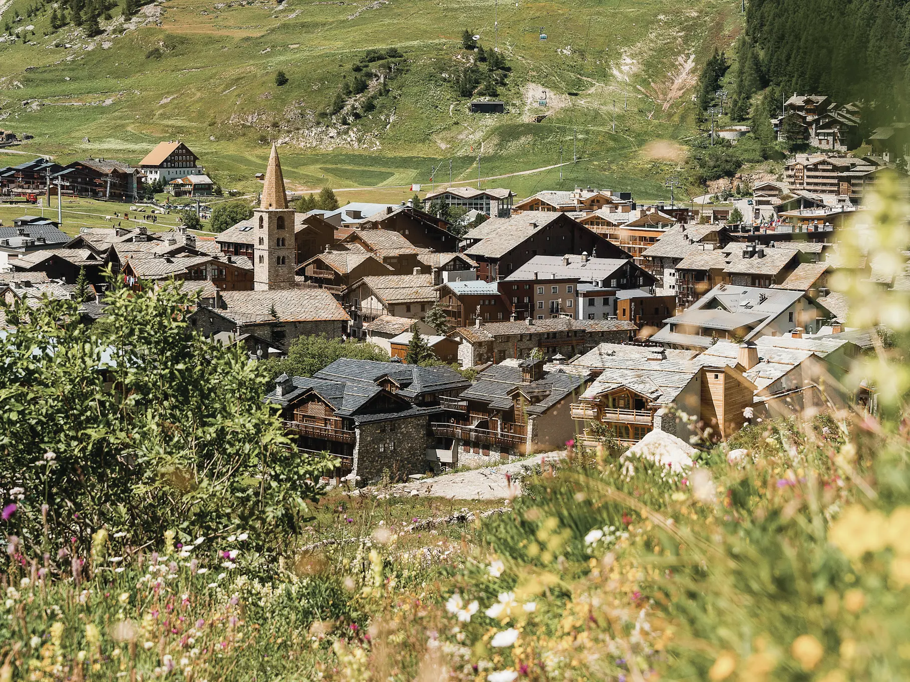 Vue ensoleillée sur le village de Val d'Isère et son clocher depuis le sentier balcon des Barmettes.