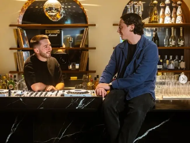 2 des 3 amis en train de discuter autour du comptoir