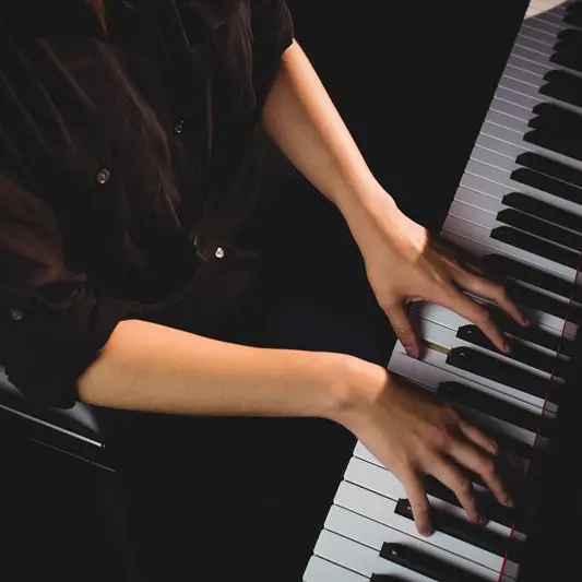 Mid-section of female student playing piano