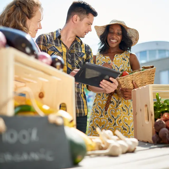 Friendly woman tending an organic vegetable stall at a farmer's market and selling fresh vegetables from the rooftop garden