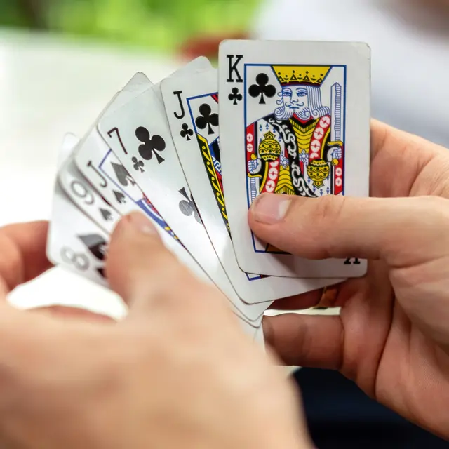 A man playing cards with other people holding a deck