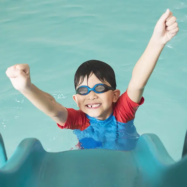 enfant-heureux-asiatique-jouant-curseur-dans-piscine