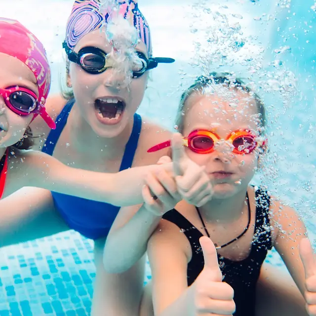 Underwater photo of young friends in swimming pool.