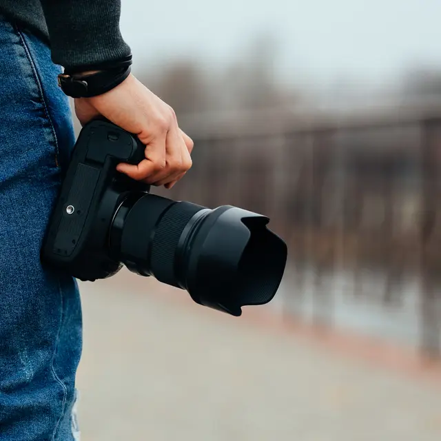 Male hands holding professional camera outdoors