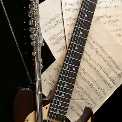 Flute, electric guitar and note sheets on black background